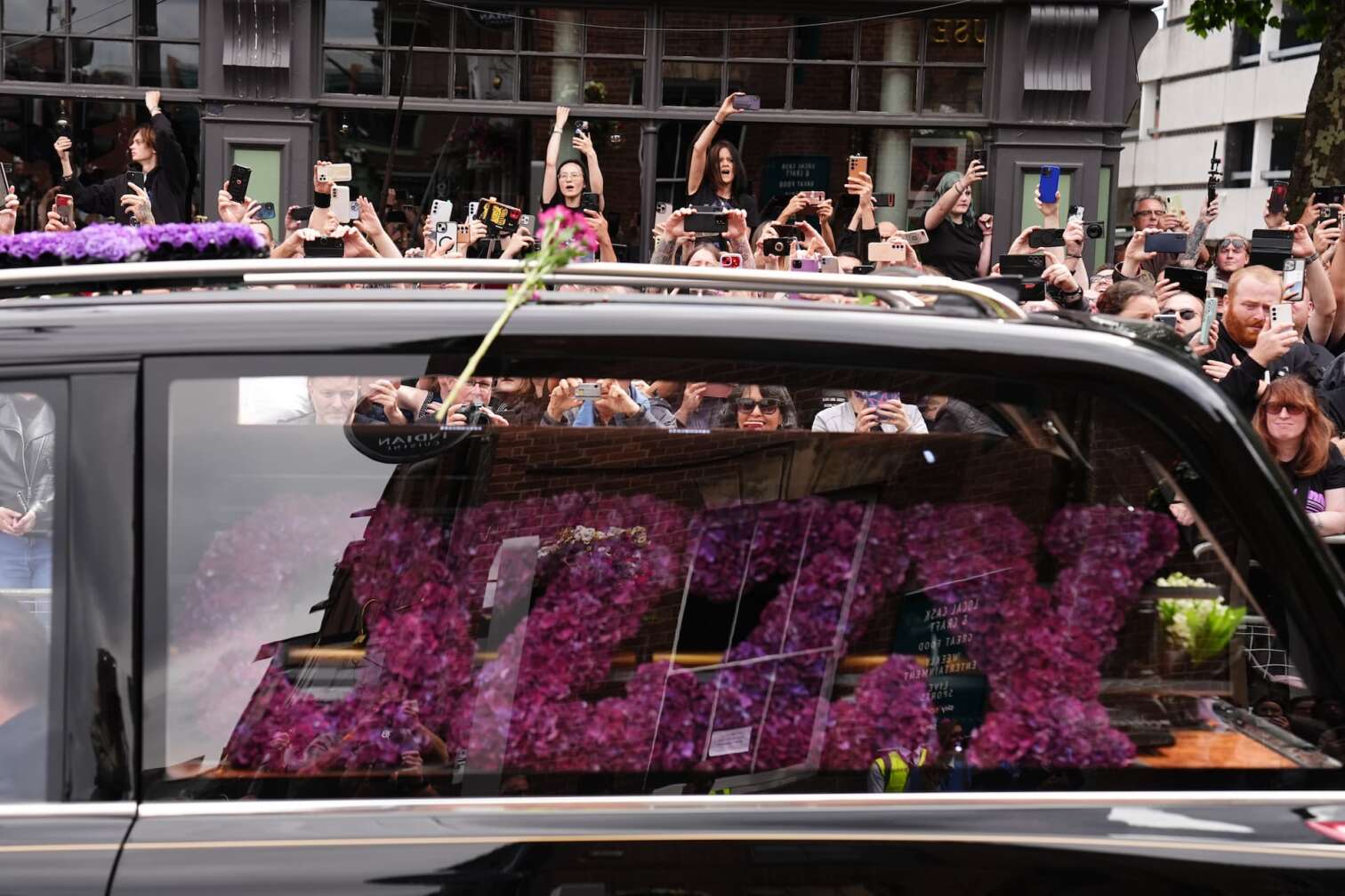 30.07.2025, Großbritannien, Birmingham: Der Trauerzug von Black-Sabbath-Frontmann Ozzy Osbourne fährt die Broad Street entlang, während sein Leichnam nach seinem Tod in der vergangenen Woche im Alter von 76 Jahren in seine Heimatstadt überführt wird. Foto: Jacob King/PA Wire/dpa +++ dpa-Bildfunk +++