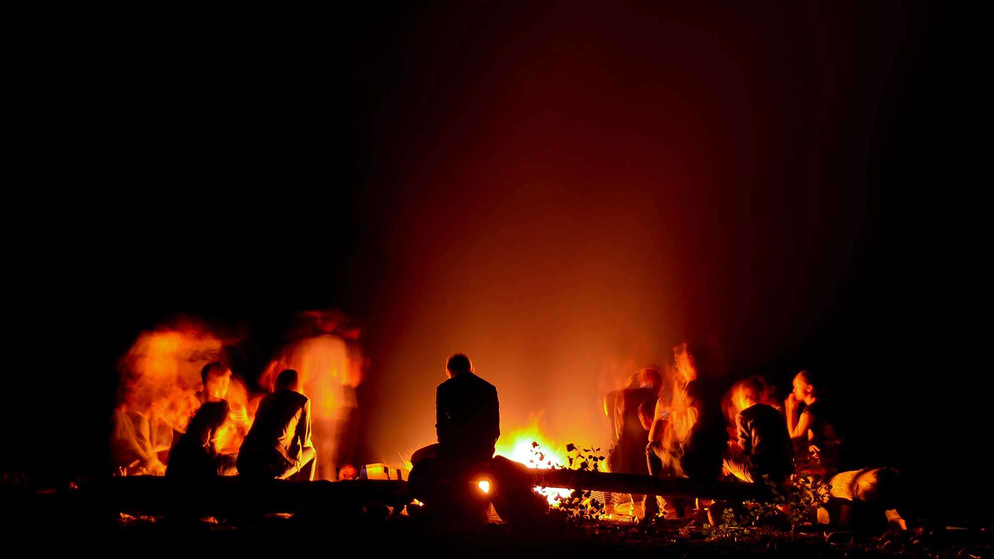 Menschen sitzen an einem Lagerfeuer