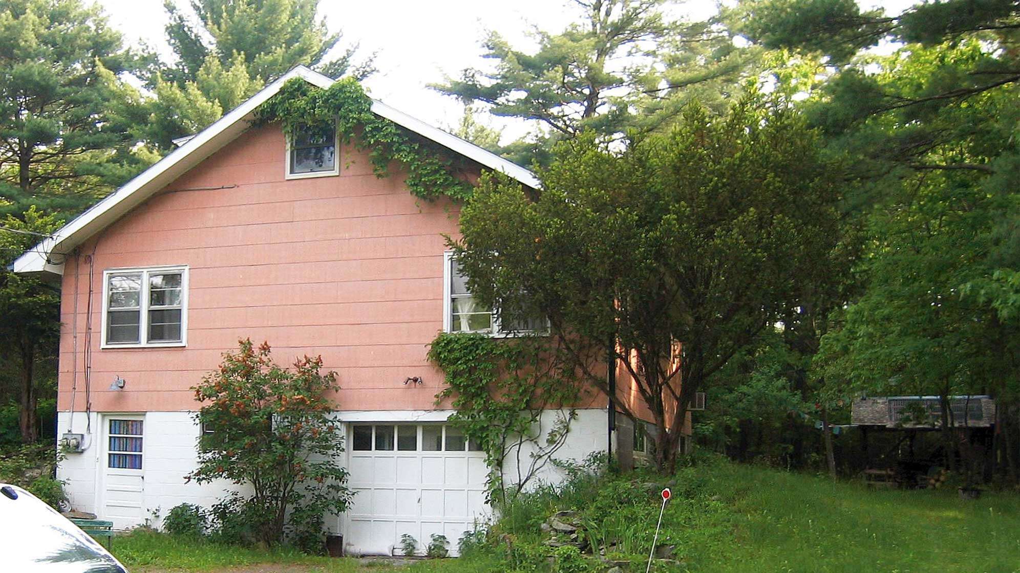 Das pinke Haus von Bob Dylan mit Garageneinfahrt im Keller und vielen Bäumen rund herum