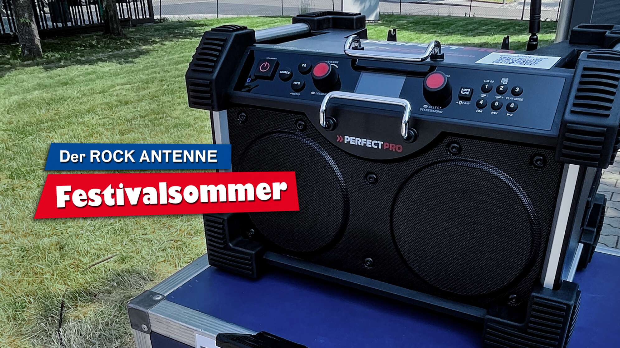 Ein DAB+ Baustellenradio des Modells "RockHart 18V" von PerfectPro auf einem Tisch im Freien, Aufschrift: "Der ROCK ANTENNE Festivalsommer"