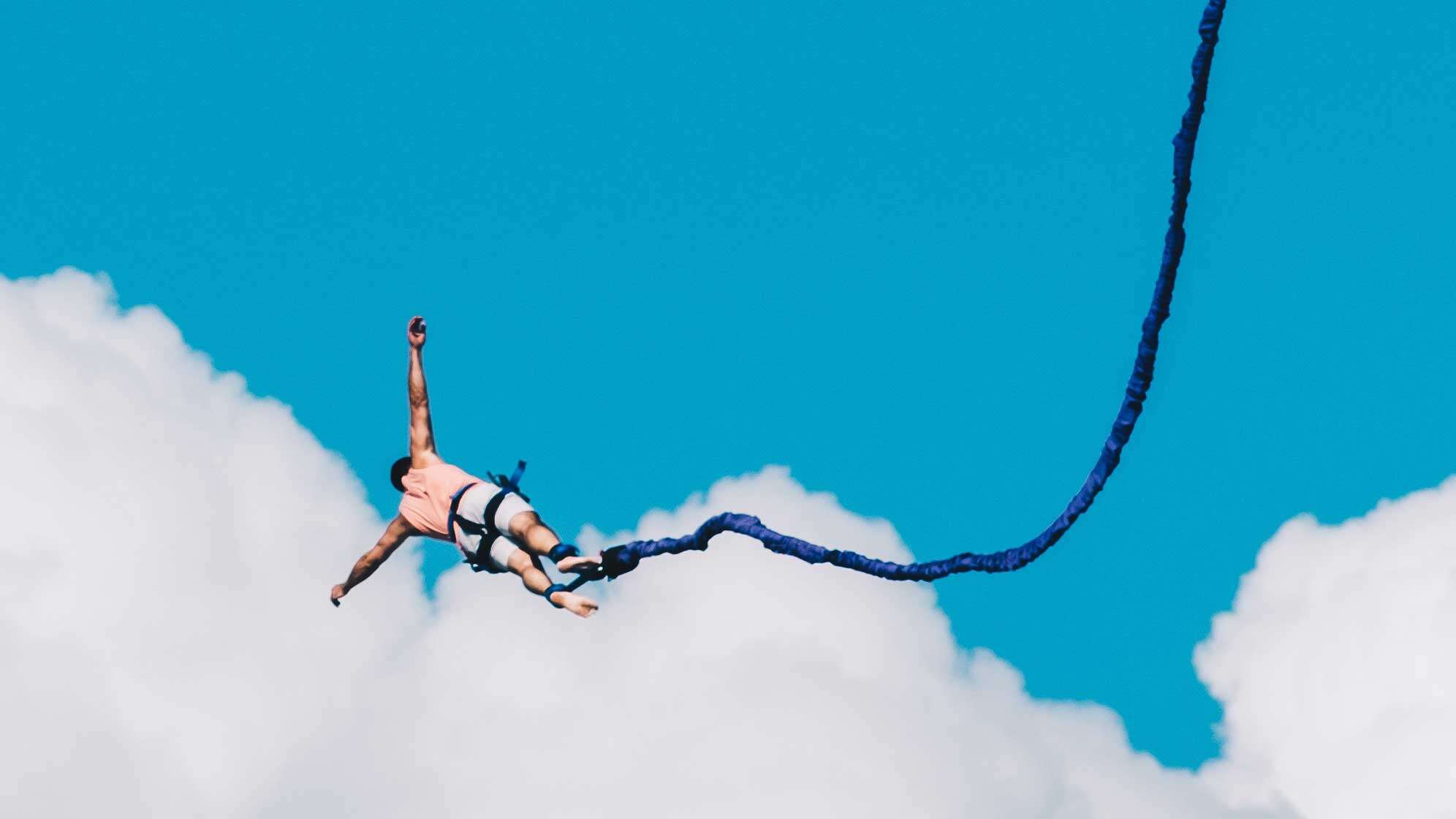 Ein Bungee-Springer in der Luft am Seil mit Blick in den Himmel