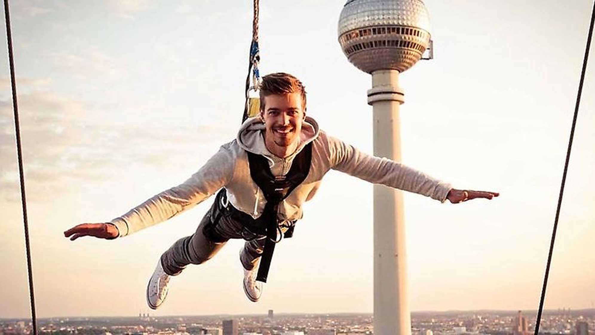 Ein Mann an einem Seil über den Dächern von Berlin