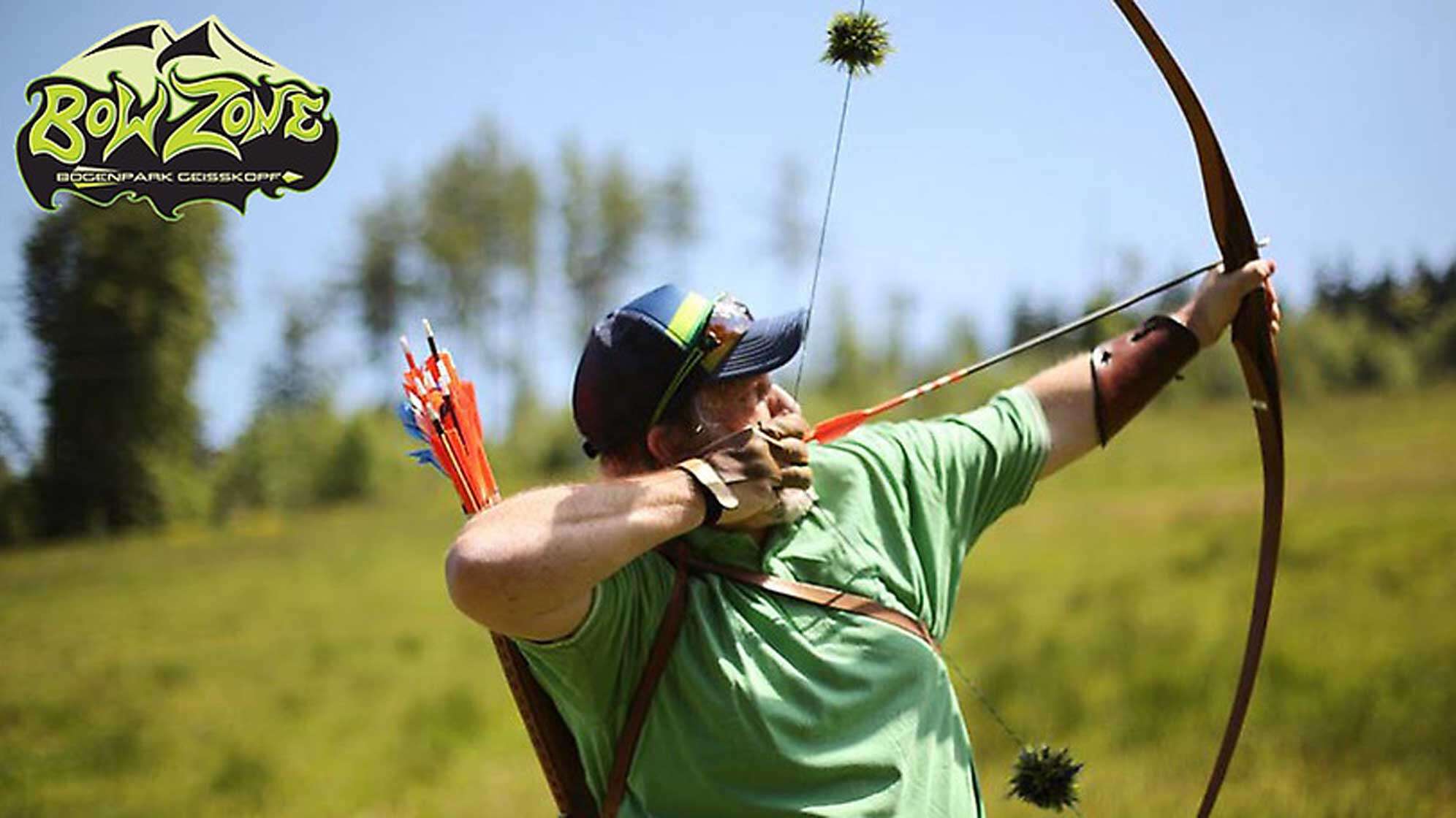 Ein Mann mit einem gespannten Bogen zielt auf eine Scheibe